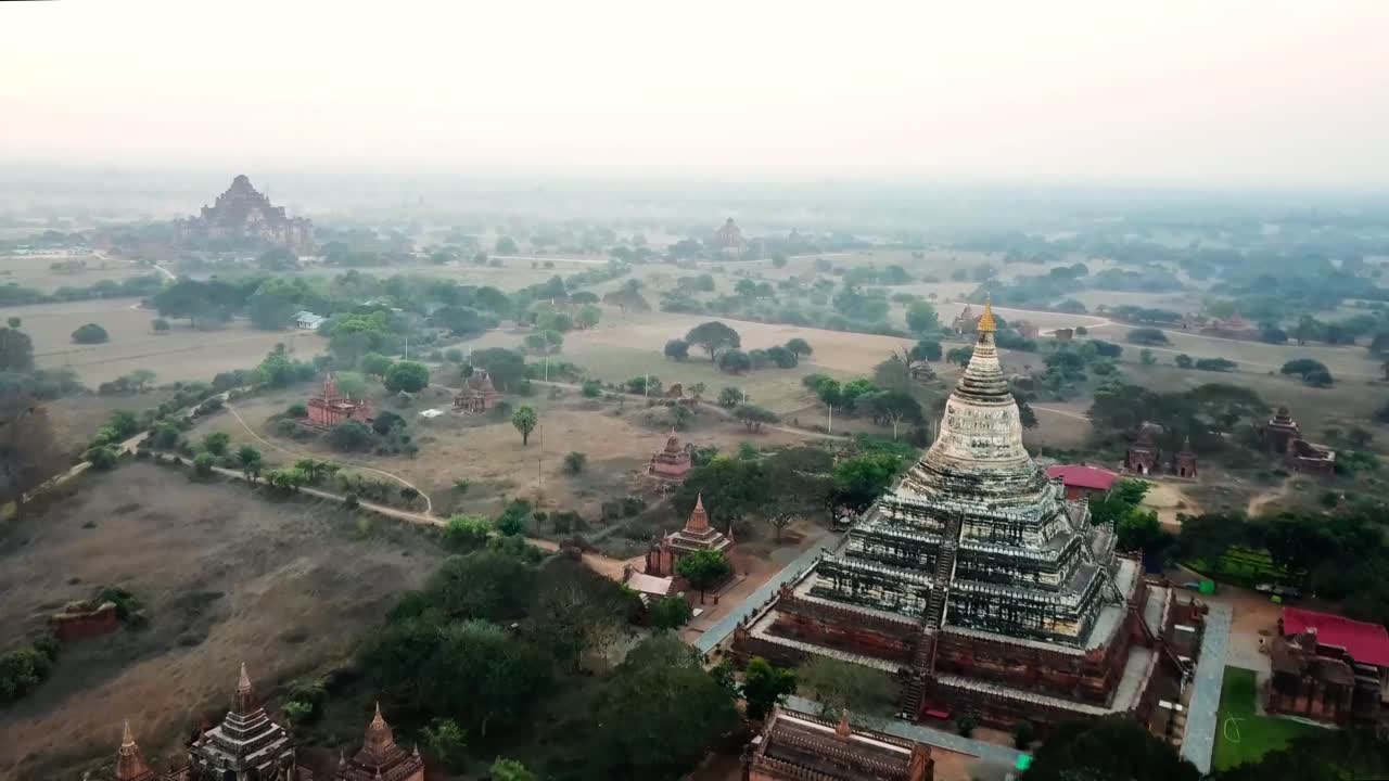 vista aérea de las históricas pagodas y templos esparcidos por las antiguas llanuras de bagan, myanmar, con árboles exuberantes y la luz dorada de la mañana creando un paisaje sereno y atemporal.