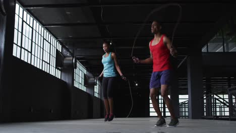 Hombre-Y-Mujer-Afroamericanos-Saltando-La-Cuerda-En-Un-Edificio-Urbano-Vacío