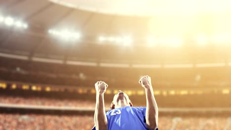 soccer player celebrates a victory and raises arms happily on the professional stadium while the sun shines