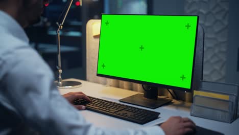 close up of a businessman working on desktop computer with chroma key green screen mock up display. male executive director managing digital projects, typing data, using keyboard and mouse.