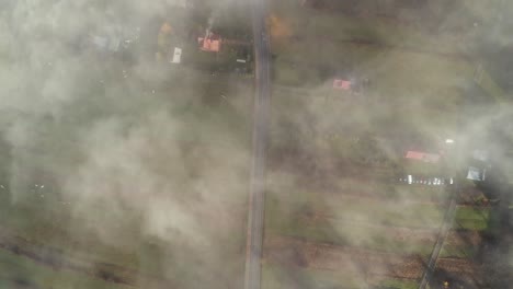 rural road passing through poland farmland covered in light mist, aerial