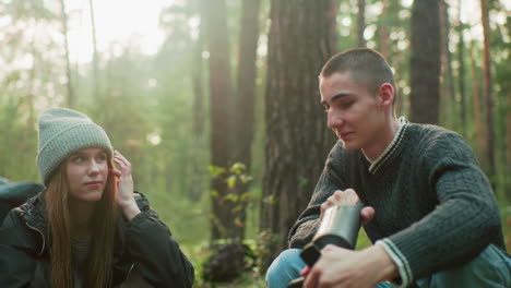 lady gazes at boyfriend in flirty manner as he focuses on pumping air during outdoor activity, capturing playful moment and emotional connection with nature in background