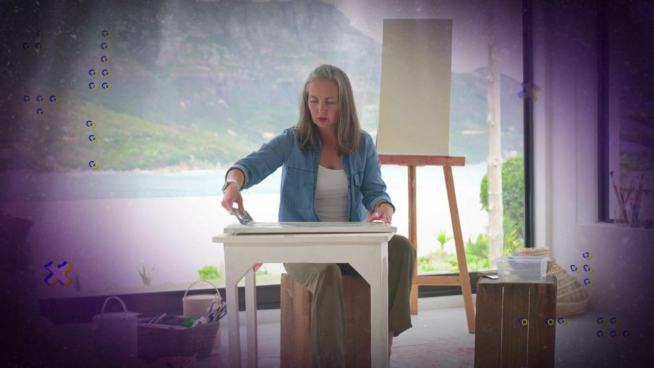 Voksen kvinne legger på duk og glatter ut bordet, forbereder underlag for kunst, med lilla merker som skjuler kantene.