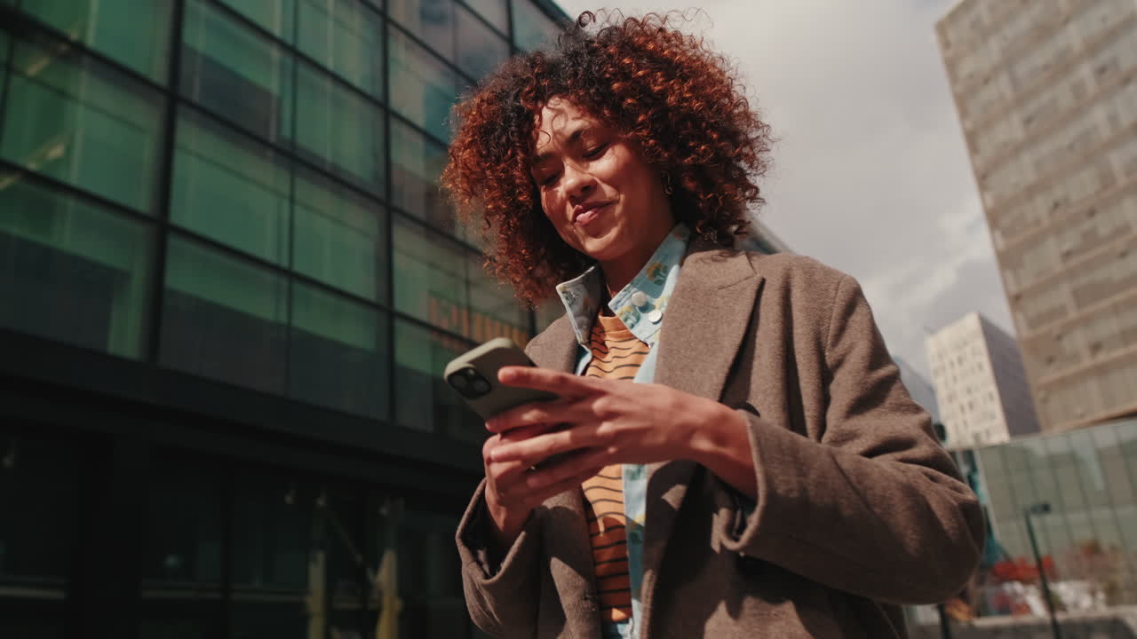 Happy Businesswoman Walks While Using Smartphone