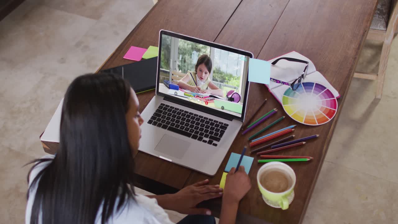maestra caucásica usando una computadora portátil en videollamada con una colegiala, tomando notas