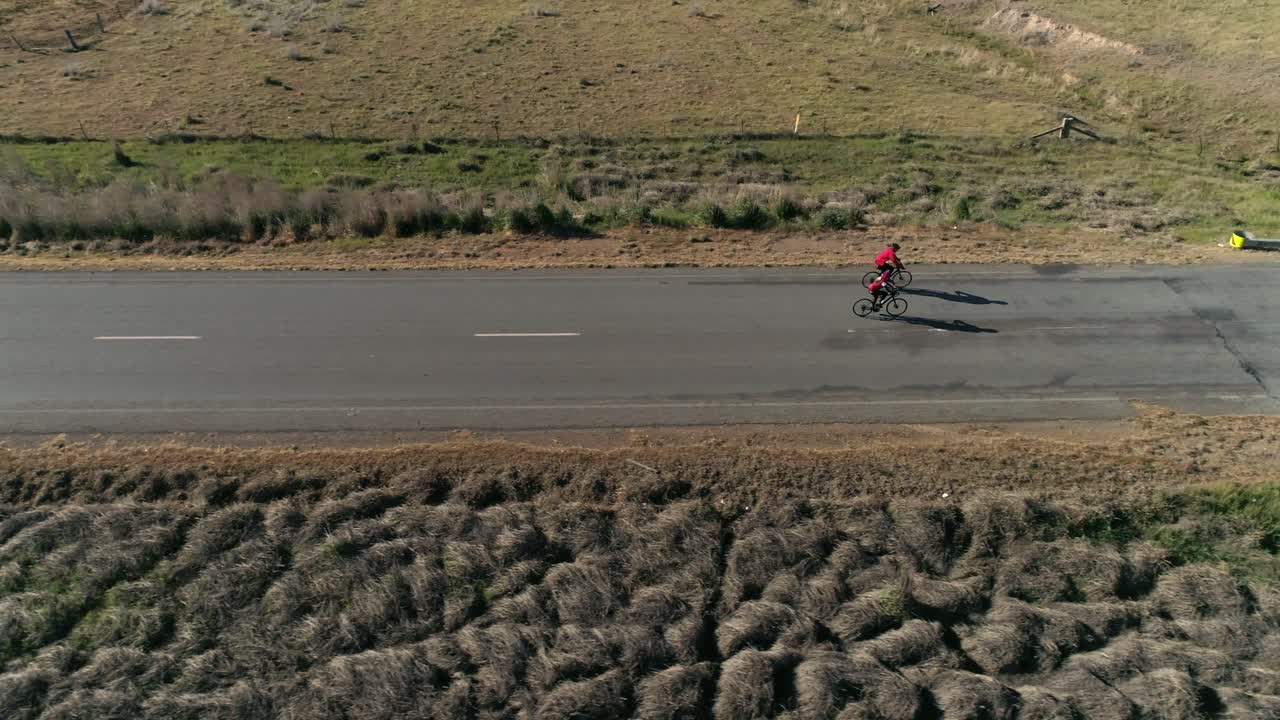 Aerial view drone tracking 2 cyclist as they approach a hill in the popular Gears and Beers race in the rural city of Wagga Wagga NSW Australia, surrounded by country landscape