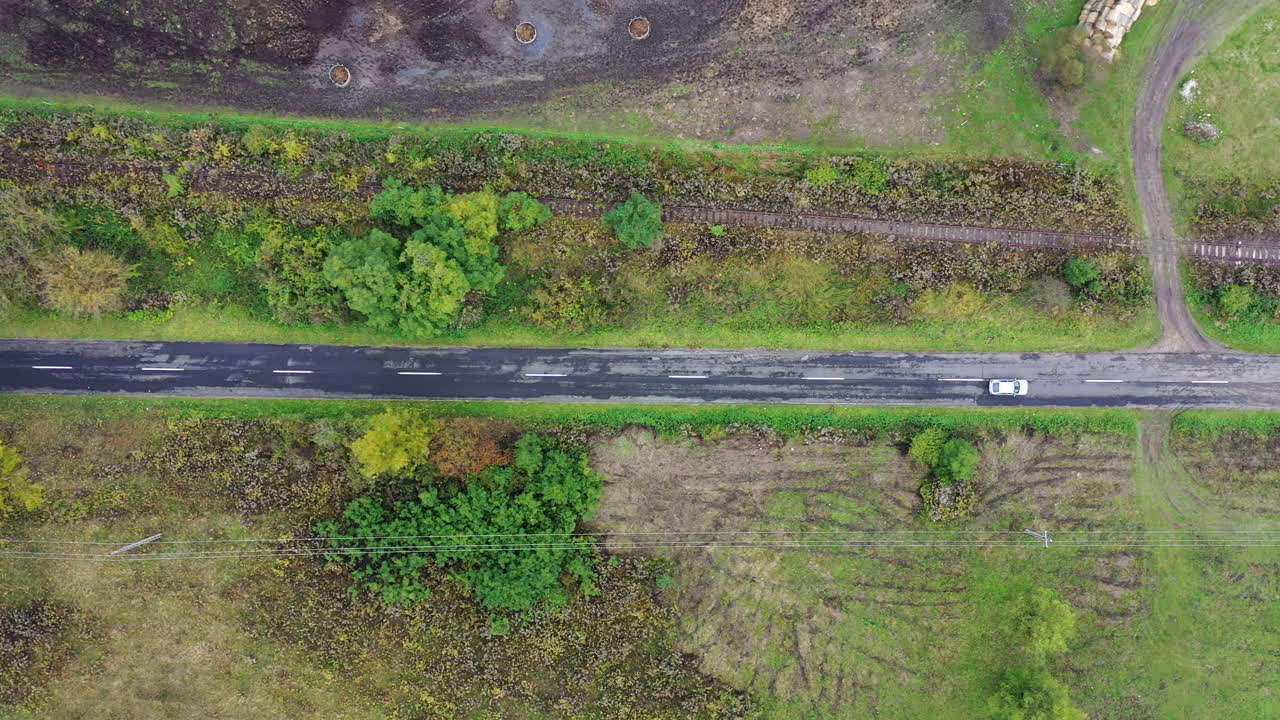 측면에 푸른 나무가 있는 2차선 도로에서 운전하는 자동차