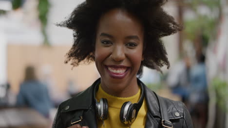 Porträt-Einer-Flippigen-Afroamerikanischen-Studentin-Im-Afro-Look,-Die-Fröhlich-In-Die-Kamera-Blickt,-Vor-Dem-Hintergrund-Einer-Lebendigen-Stadt