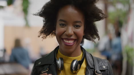 portrait of funky african american woman student afro smiling cheerful looking at camera in vibrant urban city background