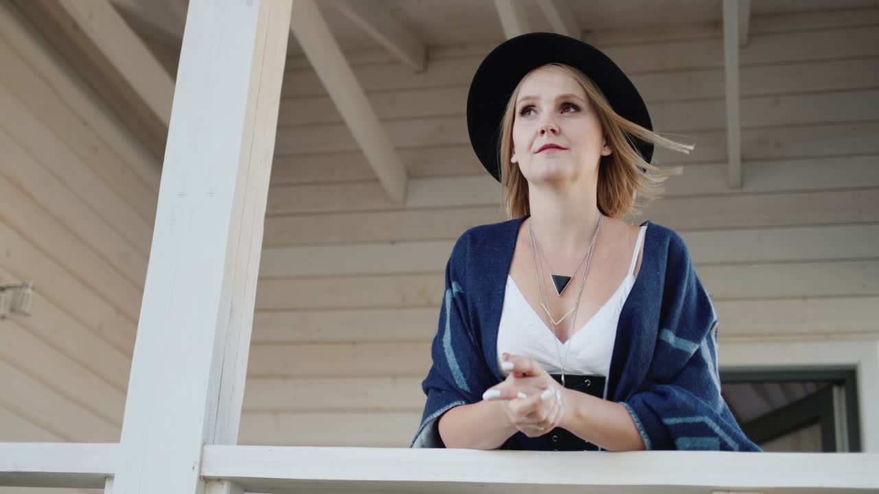 베란다에 모자와 판초를 쓴 세련된 여성의 초상화