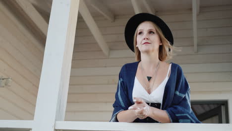 portrait of a stylish woman in a hat and poncho on a veranda