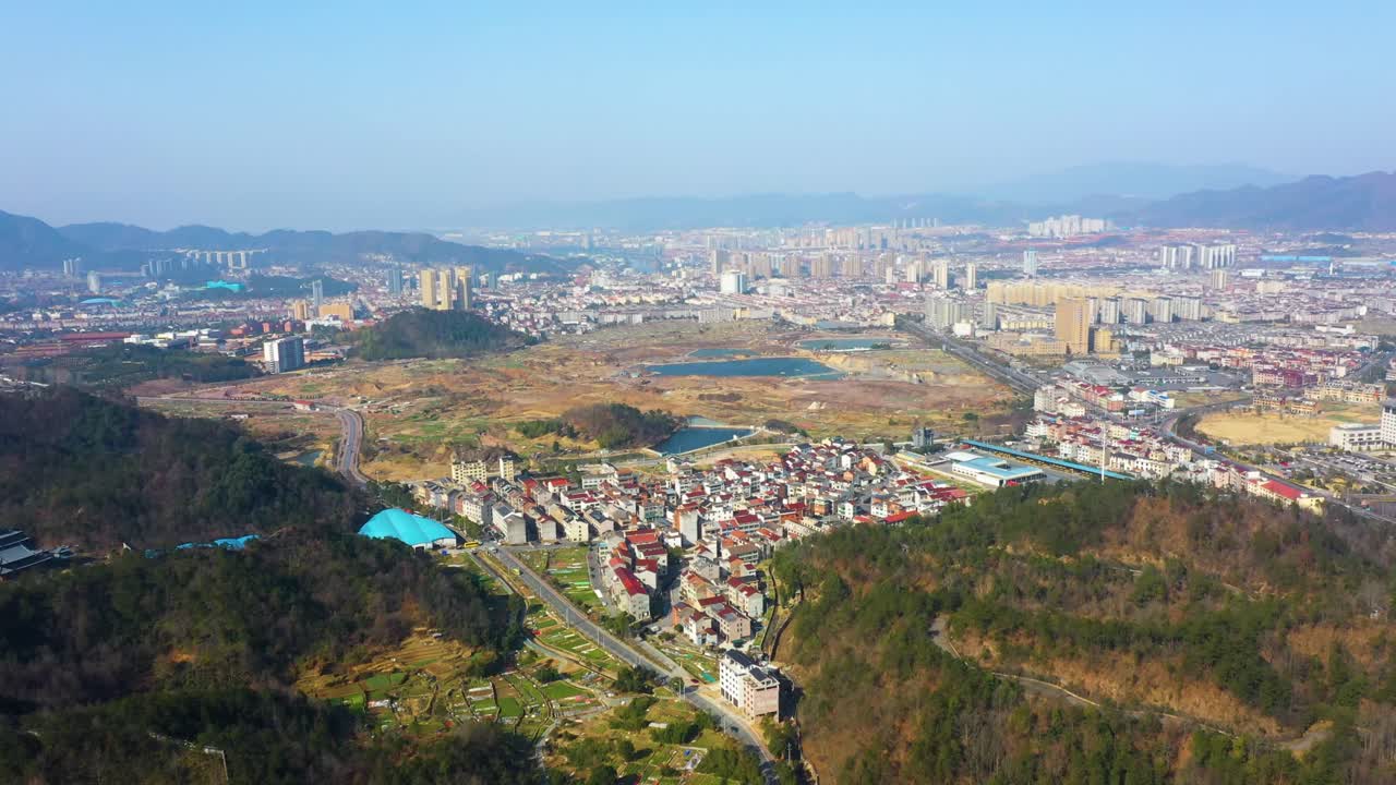 Aerial view of Chizhou City in Anhui Province, China, showcasing the blend of urban development and surrounding natural landscapes. The city’s outskirts are visible, with modern buildings rising.