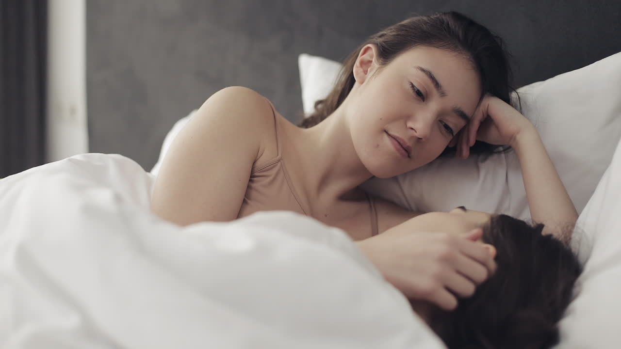Two women embracing in bed