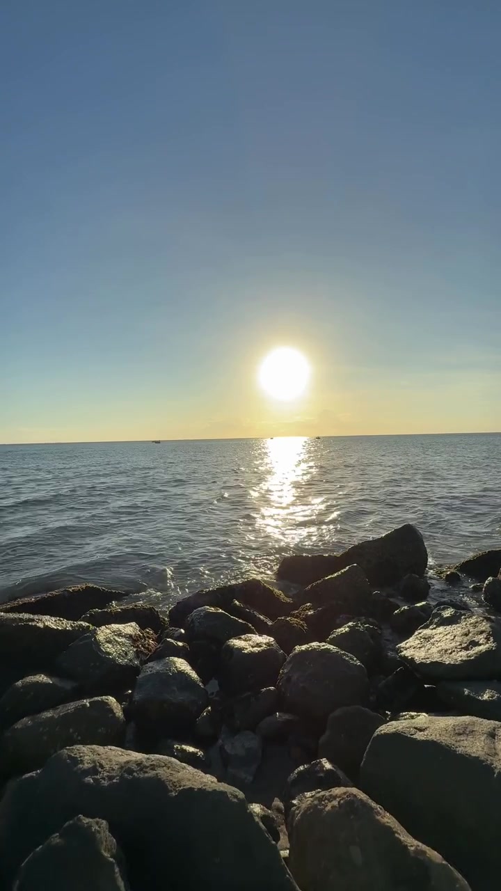 Tramonto sul mare calmo e scogli costieri