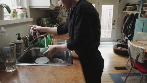 tilting shot of a hip looking person doing dishes