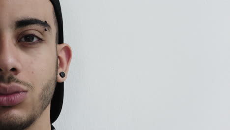 cerca de la mitad de la cara joven hombre hispano sonriendo feliz usando piercings en fondo blanco espacio de copia
