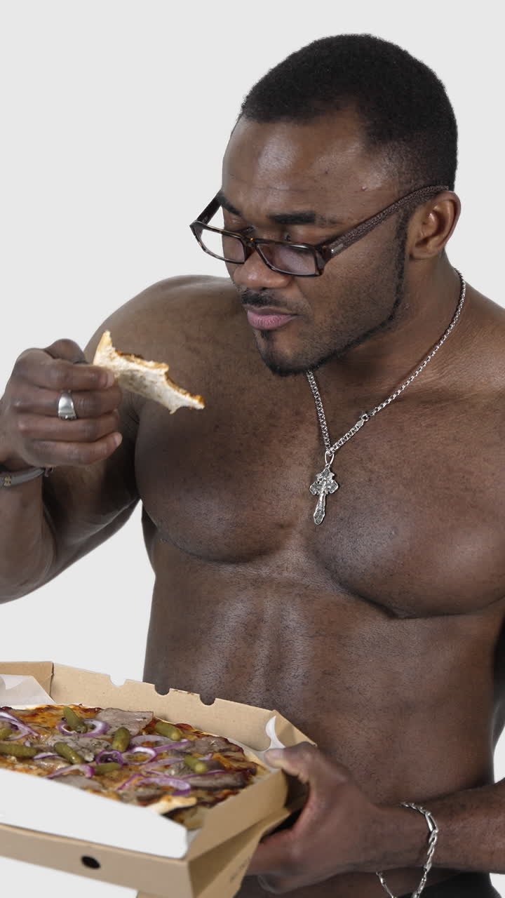 African male eating pizza. Fit young african man with beautiful torso eating pizza