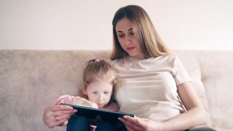 Cu-4k-Joven-Atractiva-Madre-Y-Dulce-Hija-Están-Sentadas-En-El-Sofá-Y-Entrenando-Usando-Una-Tableta