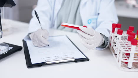 hands writing, clipboard and blood test tube