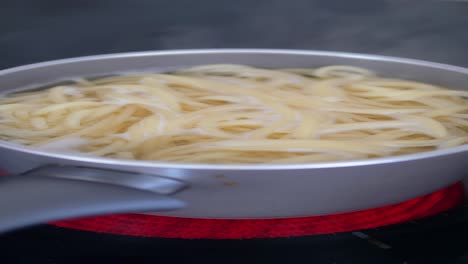 spaghetti cooking in a pot on a stove