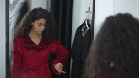 woman trying on a red dress in a fitting room