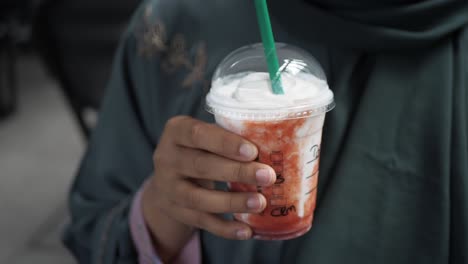 a woman is holding a strawberry smoothie with a green straw