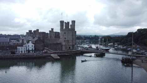 ancient caernarfon castle welsh harbour town aerial view medieval waterfront landmark descending to small boat