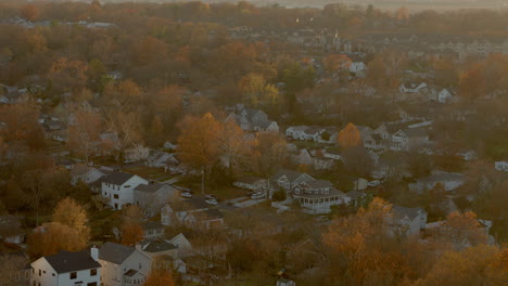 aerial of a nice neighborhood at sunset with a slow rise to reveal the horizon