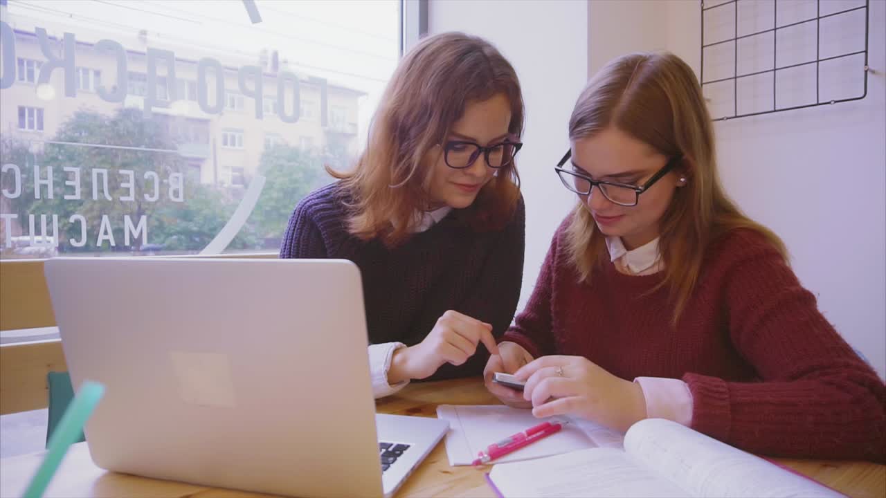 dos mujeres estudiando juntas en un café