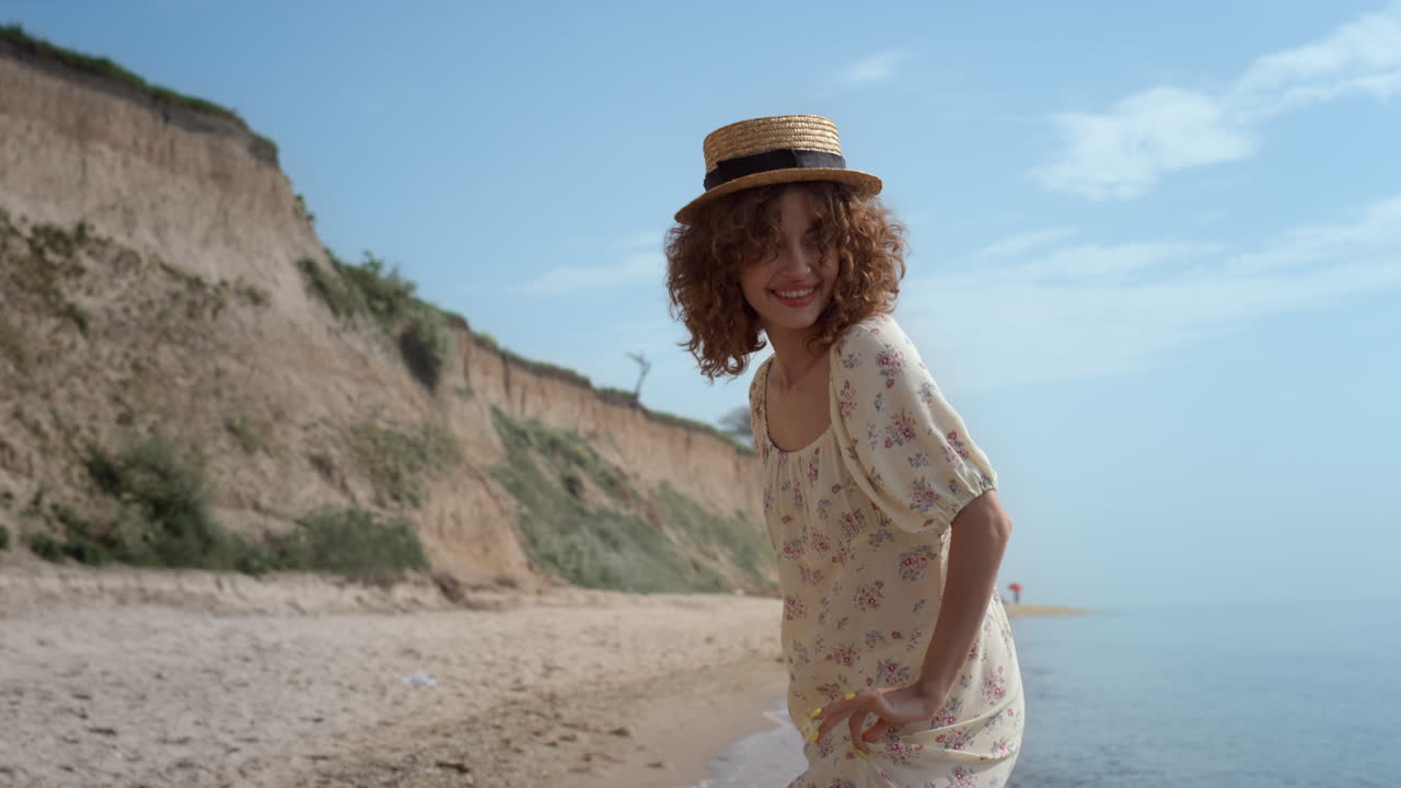 chica rizada linda bailando en las olas del océano sosteniendo el vestido. mujer sonriente divertirse.