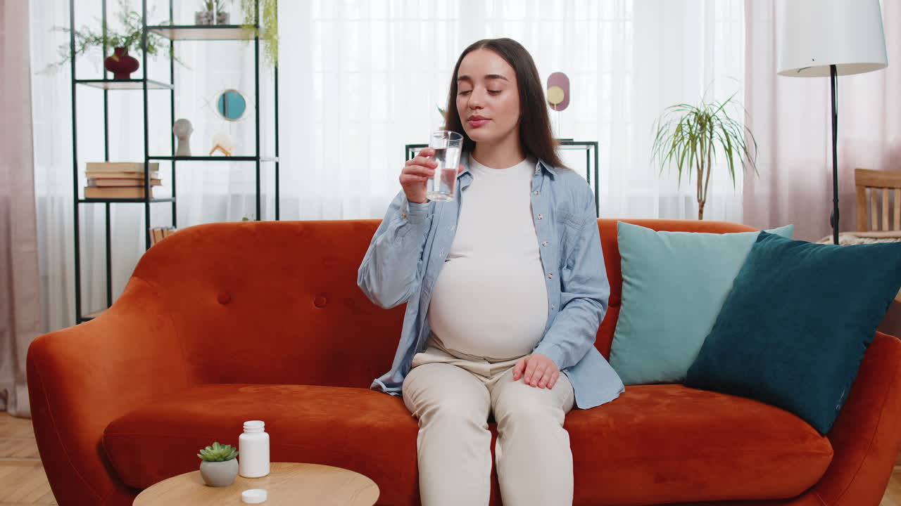 임신 중인 젊은 여성은 마약을 복용하고 태어나지 않은 아이에게 영양을 공급하기 위해 물을 마시며 건강한 임신 개념을 가지고 있습니다.