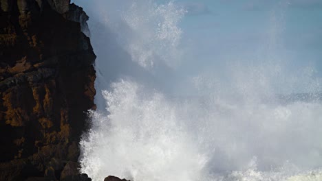 large waves roll into the coast of hawaii in slow motion and break along a craggy coast 1