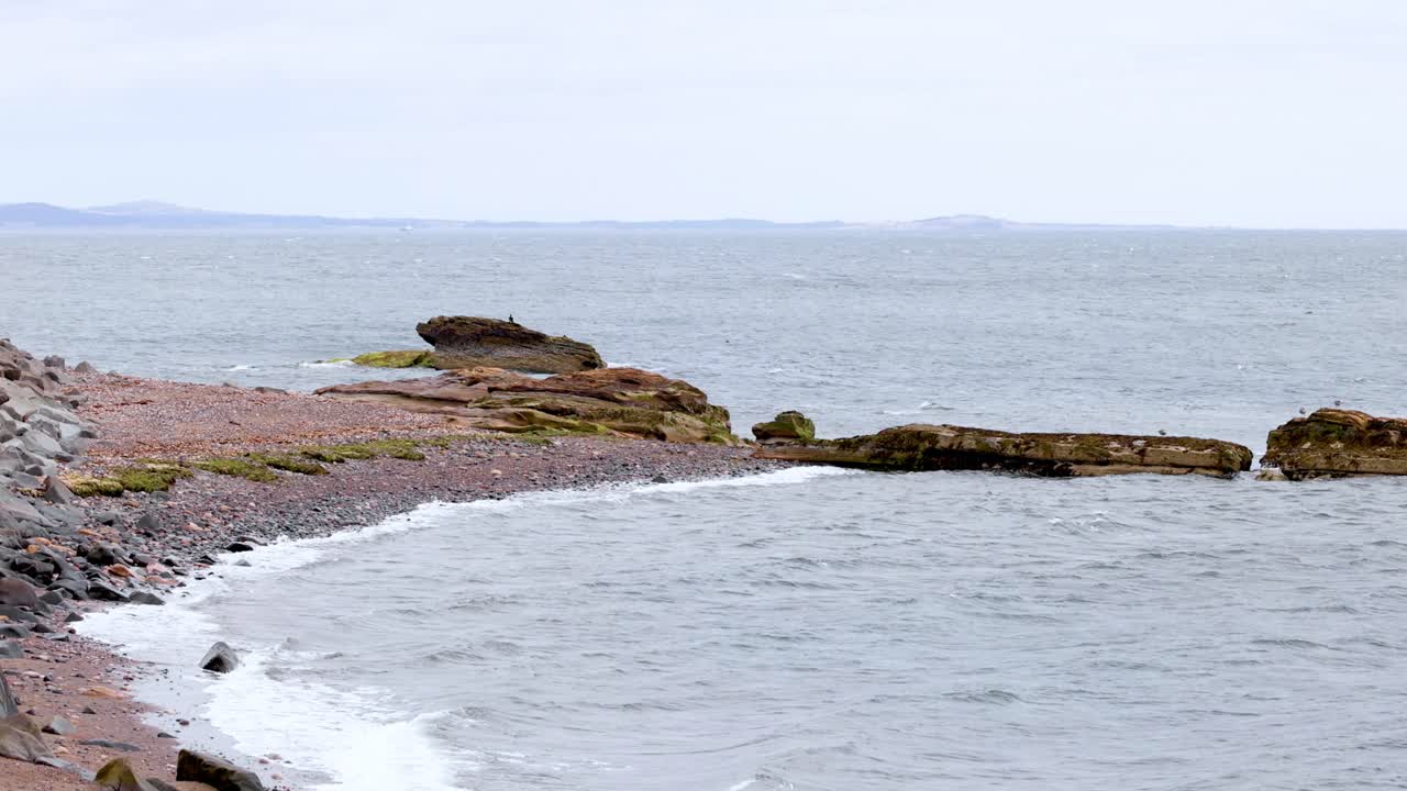 волны разбиваются на скалистом берегу в шотландии.