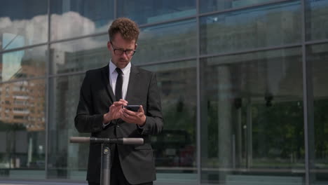 businessman using smartphone near electric scooter