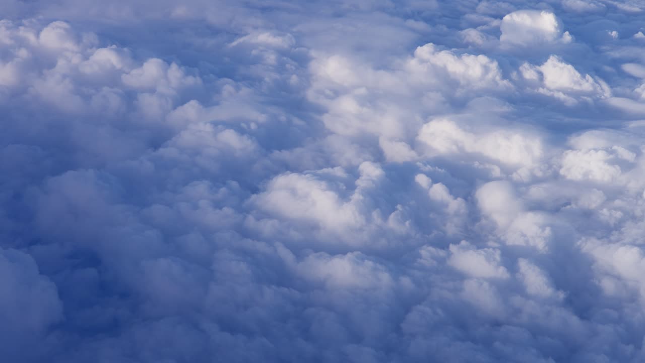 Aerial view above fluffy clouds, showcasing soft textures and bright sky scenery