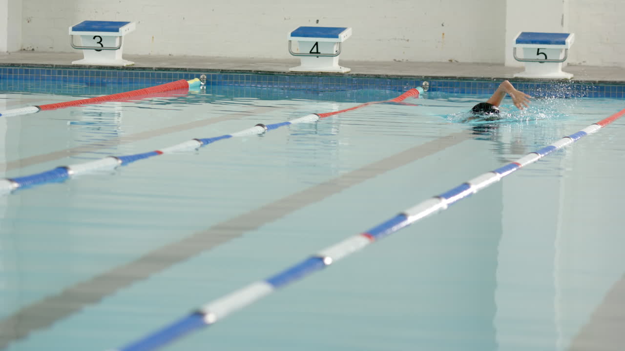 Swimming in lane, athlete practicing freestyle stroke in indoor pool, copy space