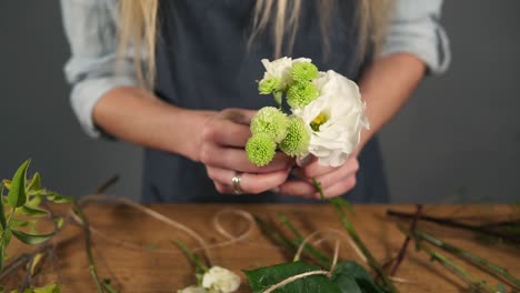 close up view of hands of professional blonde female floral artist arranging beautiful bouquet at flower shot. floristry