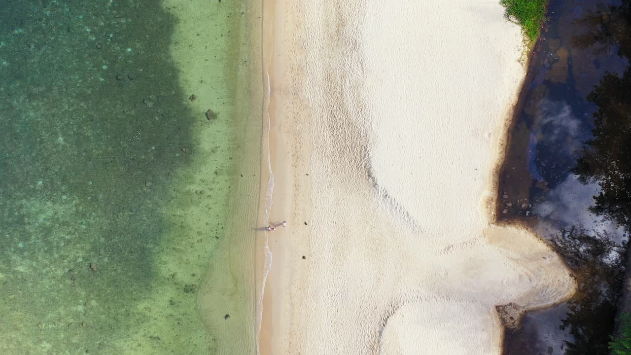 Tranquilla spiaggia esotica con sabbia bianca incontaminata sulla riva di un'isola tropicale bagnata da una calma laguna turchese in Malesia.