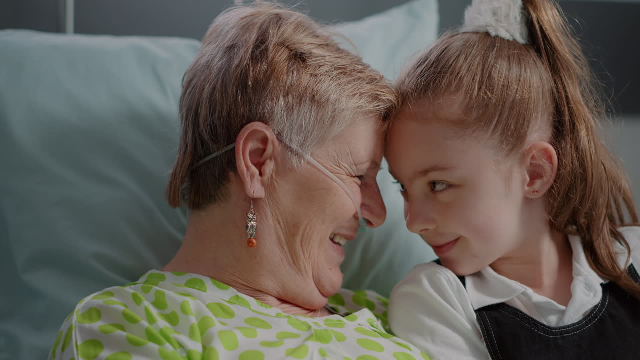 Close up of senior woman with illness enjoying visit from litte girl