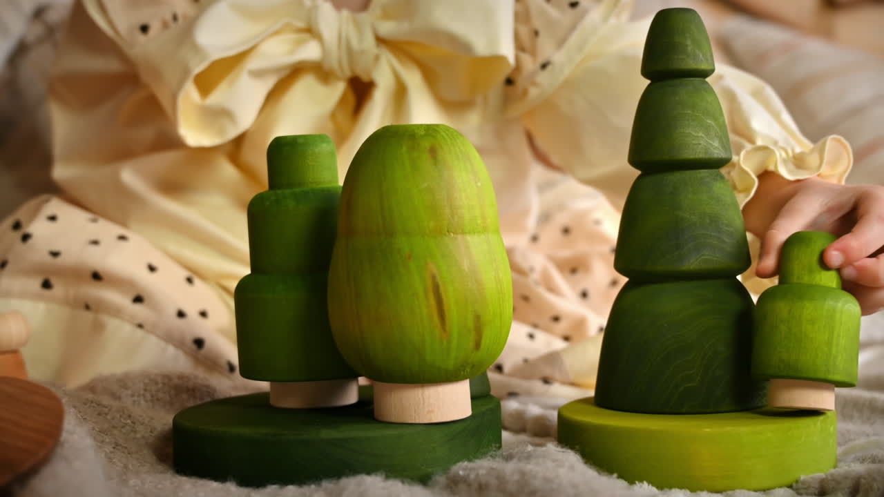 Little girl playing with several green wooden tree toys. Ecological and sustainability concept