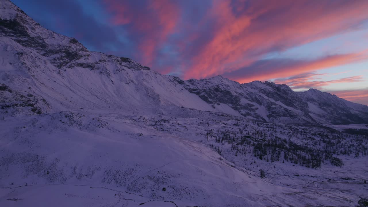 Vista aerea di bellissime montagne innevate e nuvole rosa drammatiche sopra