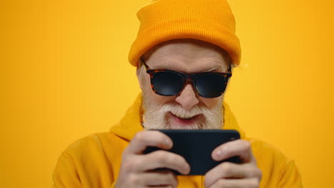 happy man looking to screen indoors. mature guy playing mobile game in studio.