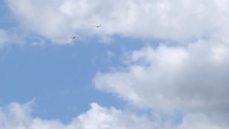 Motor-plane-pulling-glider-in-blue-cloudy-sky,-view-from-bellow