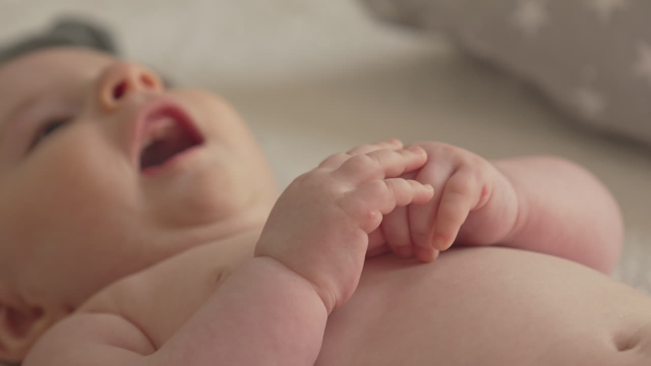 manos del bebé, parte superior del cuerpo, recién nacido en estado de ánimo lúdico, sonriendo, vestido de blanco dormitorio