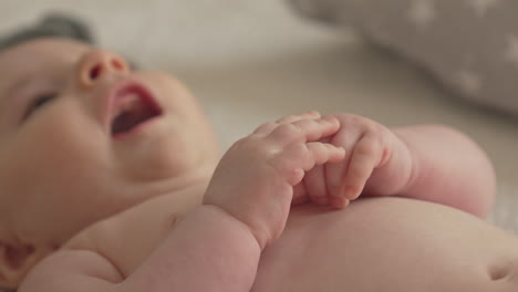 baby's hands, upper body, newborn in playful mood, smiling, dressing white bedroom