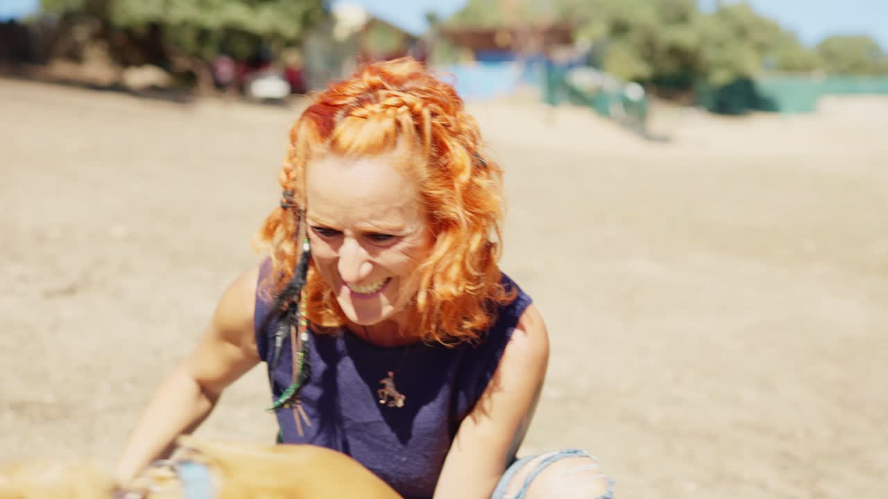 A woman joyfully interacts with her two dogs outdoors on a sunny day.