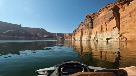 cruising on waters of lake powell with mirrored reflections of steep sandstone walls