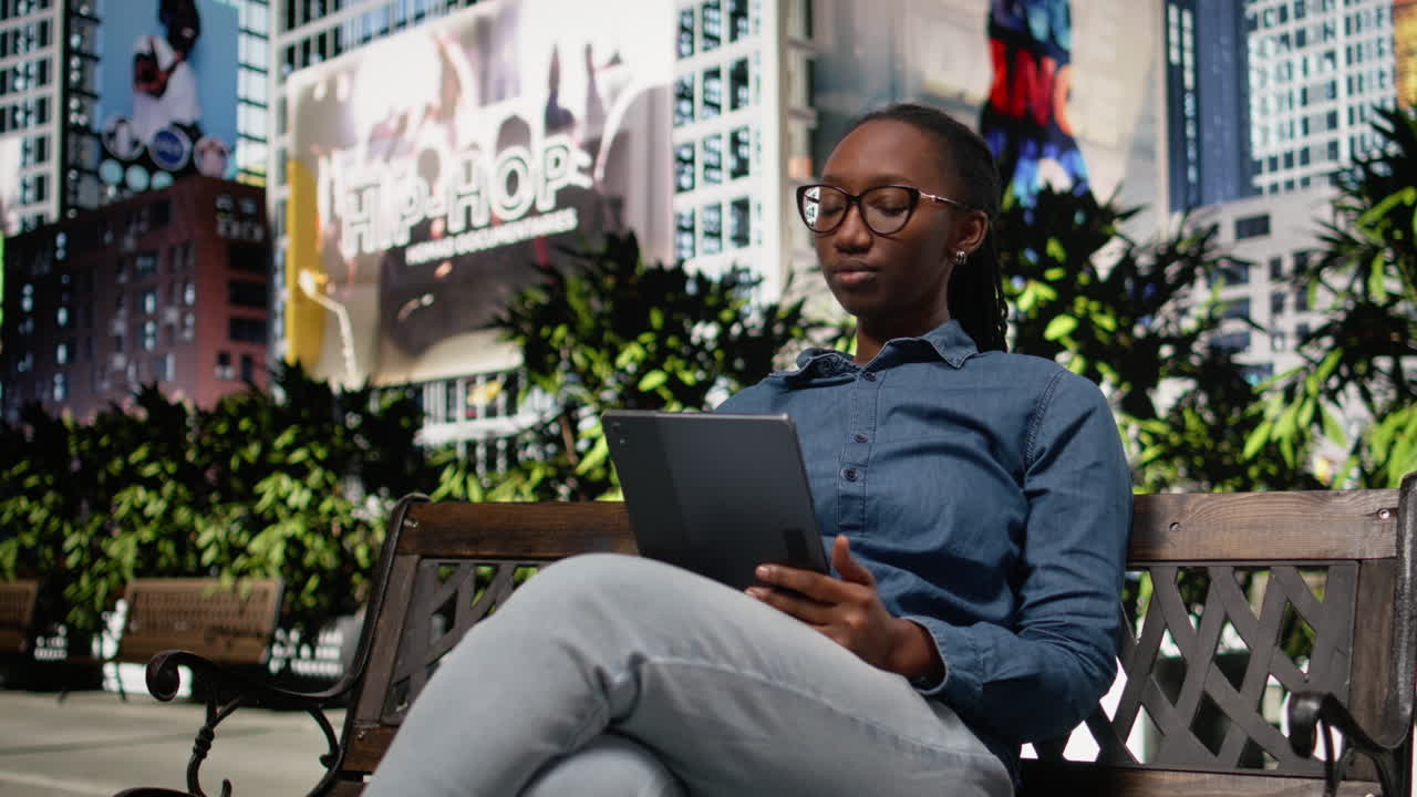 African american joyous girl using tablet to read e-books walking in city