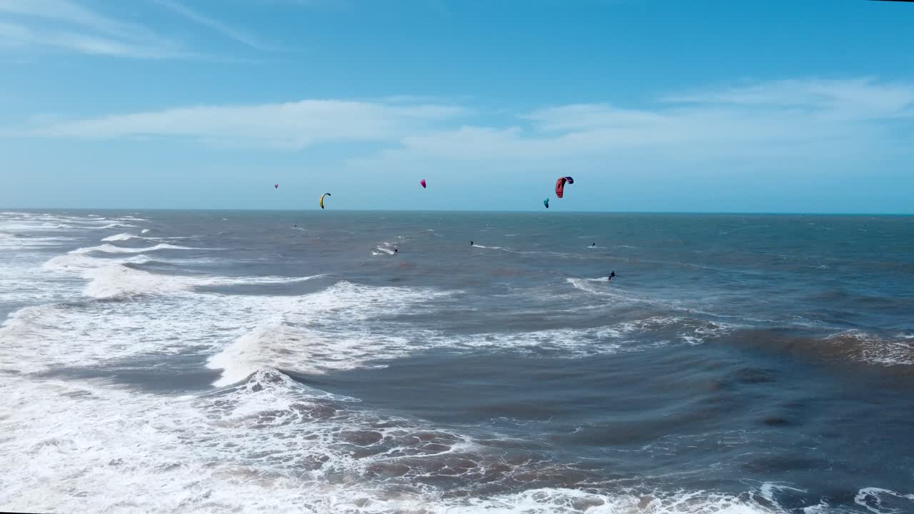 grupo de kitesurfistas montando en el océano ondulado