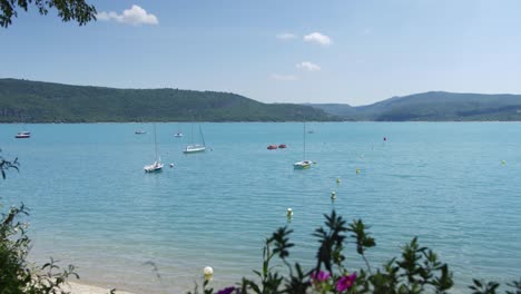 Zeitraffer:-Boote-Schwimmen-In-Einem-Blauen-See-In-Frankreich-Mit-Hügeln-Im-Hintergrund